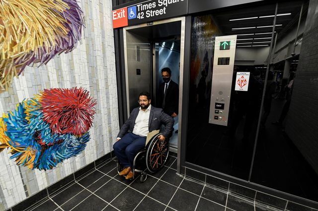 The new Nick Cave mural, which is vivid with colors and forms that look like pom poms, next to the elevator in the station. Quemuel Arroyo. the MTA's new chief accessibility officer. is in a wheelchair and exits the elevator.